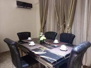 a dining room table with black chairs and a black table with flowers at Carlton Swiss Grand Hotel in Enugu