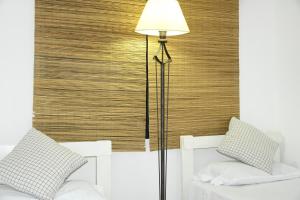 lámpara de pie en un dormitorio con 2 camas blancas en Alojamiento Las Camelias en Concordia