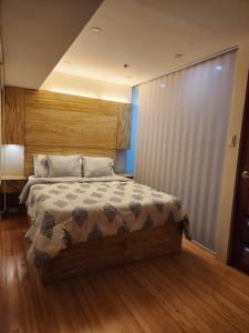 Schlafzimmer mit einem Bett und Holzboden in der Unterkunft BGC Rustic-Themed Condo near Burgos Circle 100mbps in Manila
