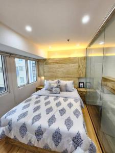 ein Schlafzimmer mit einem großen Bett und einer Glaswand in der Unterkunft BGC Rustic-Themed Condo near Burgos Circle 100mbps in Manila