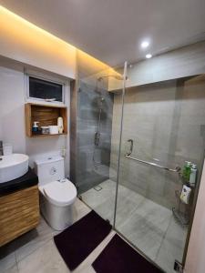 ein Bad mit einer Dusche, einem WC und einem Waschbecken in der Unterkunft BGC Rustic-Themed Condo near Burgos Circle 100mbps in Manila