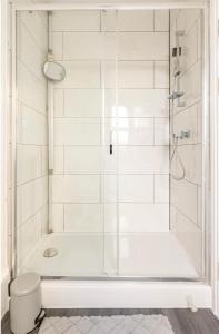 uma casa de banho com um chuveiro e uma banheira branca em New renovated studio flat with separate kitchen and bathroom em Southall