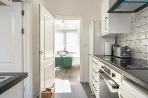 a kitchen with white cabinets and a door to a room at New renovated studio flat with separate kitchen and bathroom in Southall