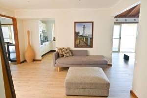 a living room with a couch and a ottoman at Lakeside Luxury in Gorokan