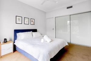 a white bedroom with a large bed and a glass door at G3 Apartment in Brisbane