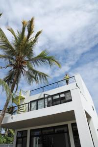 un homme debout sur le balcon d'une maison avec un palmier dans l'établissement Yachtman's House- Matara Fort, à Matara