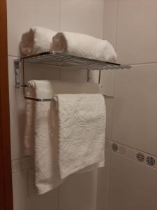ein Badezimmer mit weißen Handtüchern auf einem Handtuchhalter in der Unterkunft APARTAMENTO A UMA QUADRA DO HARD ROCK CAFÉ GRAMADO in Gramado