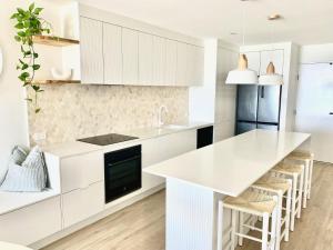 cocina con armarios blancos y encimera blanca en Monterey Lodge - Unit 18, 27 Warne Terrace, Kings Beach Caloundra, en Caloundra