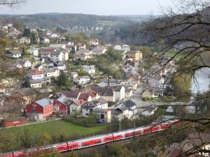 a train is traveling through a town with houses at FeWo An der Bruecke in Solnhofen +6 photos