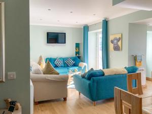 a living room with a blue couch and chairs at Ardstinchar Mews in Ballantrae