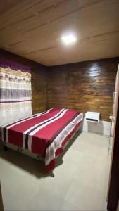 1 dormitorio con 1 cama con manta roja y blanca en ALQUILER CABAÑA EN SAN JAVIER- TUCUMÁN in 