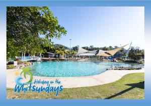 a pool at a resort with a sign that reads happy in the holidays at Marina views at Airlie 10F - 1 bedroom in Airlie Beach