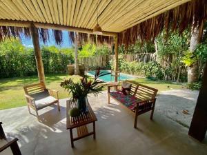 a patio with two chairs and a table and a pool at Casa do cajueiro in Praia do Espelho