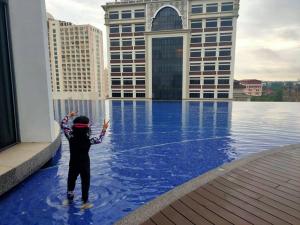 a child standing on the edge of a swimming pool on a building at Izz'man Homestay Level 33 Troika Kota Bharu in Kota Bharu
