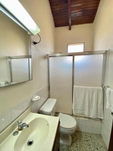 a bathroom with a sink and a toilet and a mirror at Villas del Mar in La Ceiba