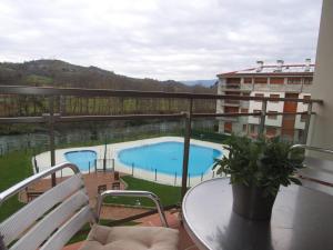 a balcony with a table and a swimming pool at Apartamento El Abuelo in Cangas de Onís