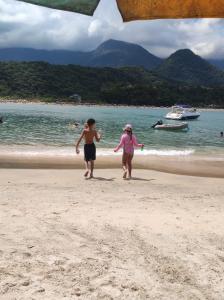 un garçon et une fille se promenant sur la plage dans l'établissement Recanto Dubay, à Caraguatatuba