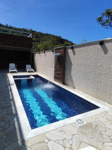 a swimming pool with two chairs next to a wall at Recanto Dubay in Caraguatatuba
