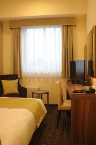 熊谷市にあるホテルサンルート熊谷駅前のベッド、デスク、コンピュータが備わるホテルルームです。
