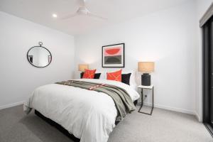 a white bedroom with a bed with red pillows at Sheppard Art House Townhouse in Bright