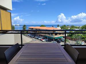 balcone con tavolo in legno e vista su un parcheggio di Studio Blue Moana - Private apartment with sea view a Papeete