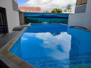 a blue swimming pool with a view of the ocean at Blue Moana Studio Papeete - Sea View, AC, Fast Wifi, Pool, Gym in Papeete