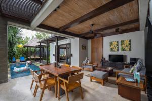 sala de estar con mesa, sillas y piscina en Le Jardin Villas Seminyak en Seminyak