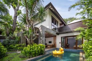 une piscine en face d'une maison avec un canard en caoutchouc dans la cour dans l'établissement Le Jardin Villas Seminyak, à Seminyak