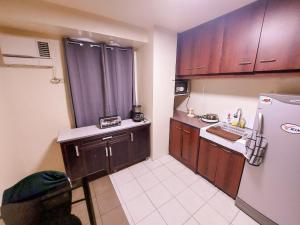a small kitchen with wooden cabinets and a refrigerator at Affordable Cozy and Peaceful Loft Condo near Cubao in Manila