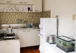 La cuisine est équipée de placards blancs et d'un réfrigérateur blanc. dans l'établissement Bird Village Guesthouse Rook, à Ulsan