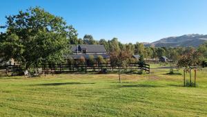 a field with a fence and trees and a house at The Stables - Farm Stay in Strath Creek
