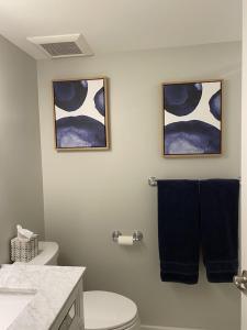 a bathroom with a toilet and two pictures on the wall at Beautiful Condo in Sun Drenched Garden in San Francisco