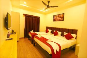 a bedroom with two beds with red and white pillows at Hotel Vijaya Grand in Srikalahasti