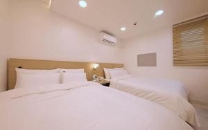 zwei Betten in einem Hotelzimmer mit weißer Bettwäsche in der Unterkunft Pier26 Hotel in Pohang + 91 Fotos