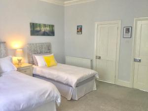 a bedroom with two beds and a lamp and a door at Glebe House in Deal