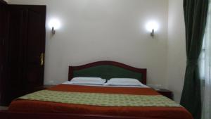 a bedroom with a bed with a green and orange blanket at Elim Homestay Fort Kochi in Cochin