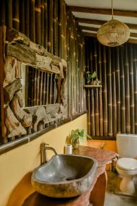 Villa Nextdoor Nature Yogyakarta في بانتول: حمام مع حوض حجري ومرحاض