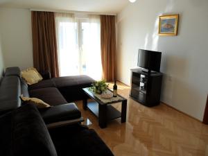 ein Wohnzimmer mit einem Sofa und einem TV in der Unterkunft Apartments Kalluka in Sveti Stefan