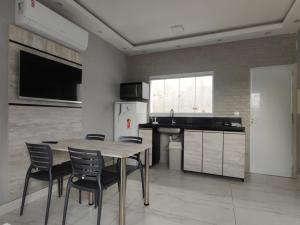 uma cozinha com uma mesa e cadeiras e um frigorífico em Recanto Dubay em Caraguatatuba