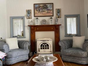 a living room with two chairs and a fireplace at Cherry Blossom Cottage-with country charm and spa in Stanthorpe