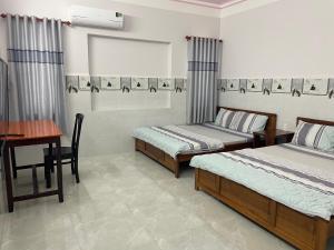 1 Schlafzimmer mit 2 Betten, einem Schreibtisch und einem Tisch in der Unterkunft Thien Ngoc Hostel in Cần Thơ