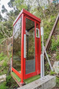 una cabina de teléfono rojo sentada en la cima de una colina en ゴンドラヴィラ イン熱海 en Atami