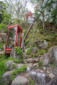 una cabina de teléfono rojo en una colina con rocas en ゴンドラヴィラ イン熱海 en Atami