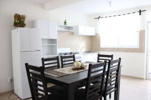 a kitchen with a table with chairs and a white refrigerator at Casa Colibri Oaxaca con Jacuzzi en Terraza in Santa María Azompa