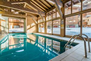 a swimming pool in a building with windows at Lagrange Vacances Les Chalets Edelweiss in La Plagne