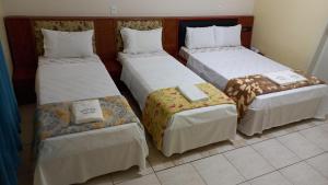 um grupo de quatro camas num quarto em Hotel Dalias em Guarulhos