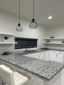 a kitchen with white cabinets and a granite counter top at Suites Marvento in Ensenada
