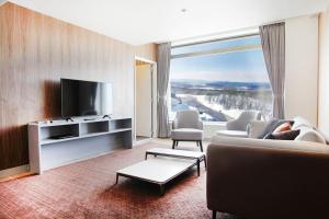 a living room with a couch and a tv at Rockwood Hotel & Spa in Ajigasawa