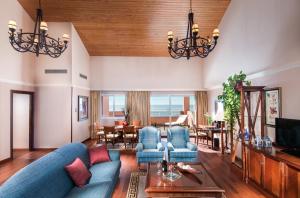 a living room with a blue couch and a dining room at Elba Estepona Gran Hotel & Thalasso Spa in Estepona