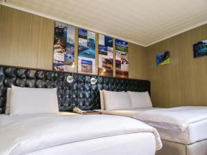 two beds in a room with posters on the wall at MF Hotel, penghu in Magong